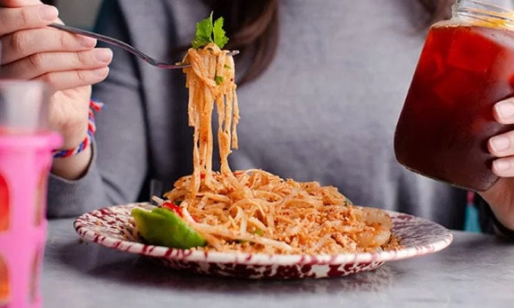 Person scooping Rosa's Thai Noodles on a fork from a mottled red plate