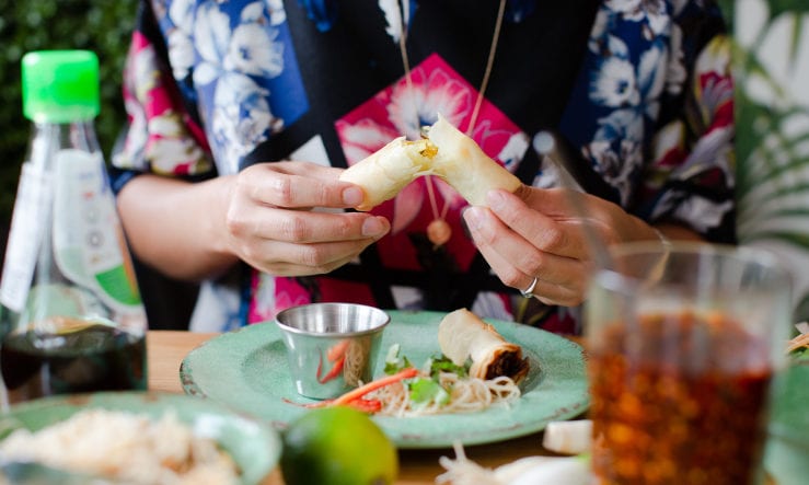 Someone eating a spring roll at a Rosa's Thai restaurant