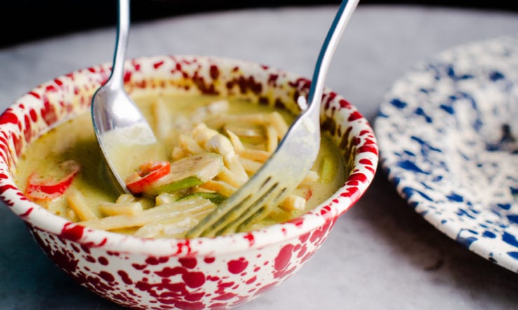 Person eating a Rosa's Massaman Curry from a bowl with a spoon and fork