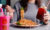 woman holding iced drink eating noodles