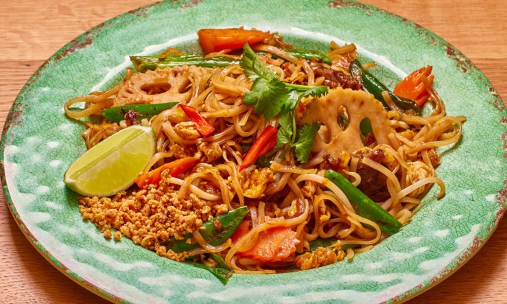 PadThaiVeg Pad Thai with vegetable served in a green plate on a wooden table