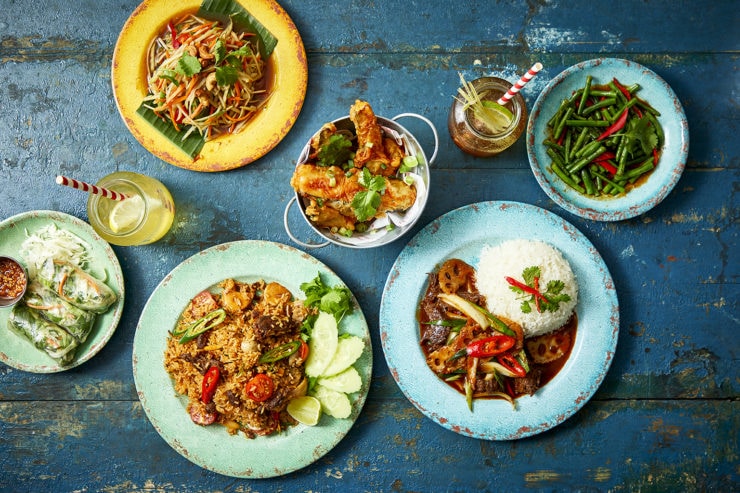 Rosa's Thai veggie dishes in mixed colour plates on blue wooden table