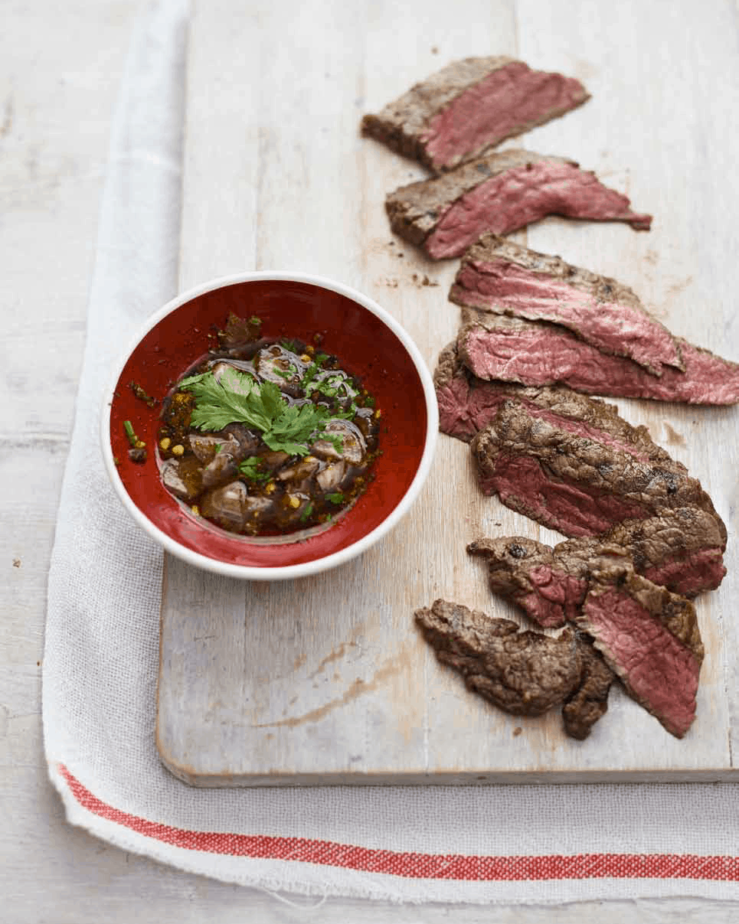 Tiger Tears beef slices on a wooden board with dipping sauce